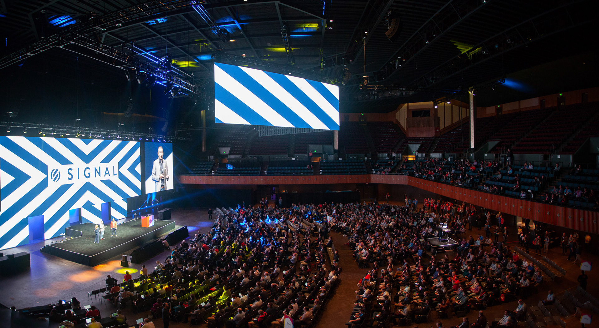Aerial wide shot of Twilio Signal arena with full audience and bold graphic stage design